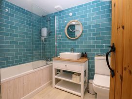 A bathroom with a bathtub, shower, sink, and toilet at Bryn Mor Cottage, Mynytho near Llanbedrog