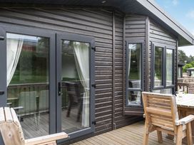 An outdoor space with wooden decking and sliding doors at Brayford Lodge Spa in Louth