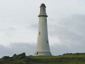A lighthouse on a grassy hill with rocks at Priory View in Ulverston