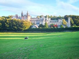 A building surrounded by trees and grass with a sheep in the field at Priory View in Ulverston