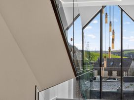 A staircase with glass railing and hanging light fixtures at Heddfan in Carmarthen