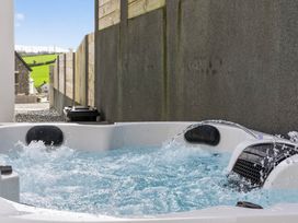 A hot tub with water and splashes near a fence at Heddfan in Carmarthen