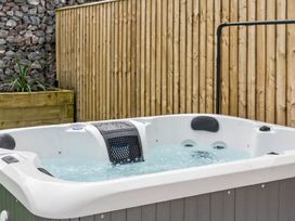A hot tub with water surrounded by rocks and a wooden fence at Ty Uchel