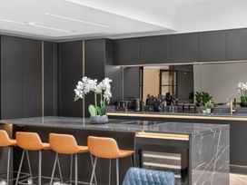 A kitchen with a countertop island and bar stools at Ty Uchel