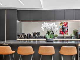 A kitchen with a countertop, bar stools, and kitchen appliances at Ty Uchel