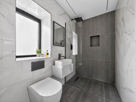 A bathroom featuring a toilet, sink, mirror, and shower at Ty Uchel