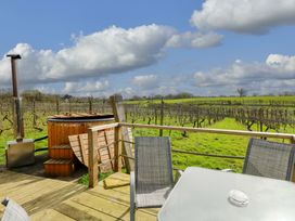 An outdoor seating area with a hot tub and vineyard view at Grape Escape near Halesworth