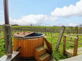 A hot tub with wooden steps and chimney near a vineyard at Grape Escape near Halesworth