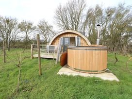 A wooden cabin with a hot tub in an outdoor setting at Grape Escape near Halesworth