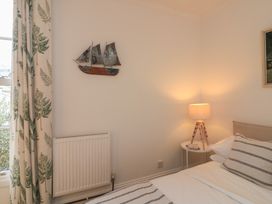 A bedroom with a bed, lamp, and wall decoration at Ivy Cottage in Dartmouth