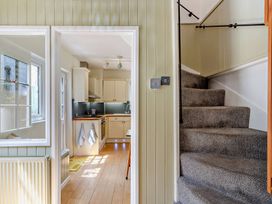 A hallway with a staircase and a view into a kitchen at Ivy Cottage, Dartmouth