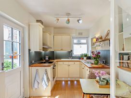 A kitchen with cabinets and a table at Ivy Cottage Dartmouth