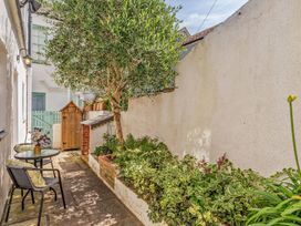 A garden with a table and chairs beside foliage at Ivy Cottage in Dartmouth