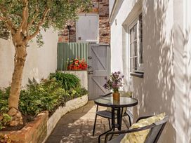 A garden with a table and chairs alongside plants at Ivy Cottage in Dartmouth