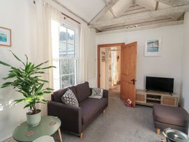 A living room with a sofa and a TV stand at Ivy Cottage Dartmouth