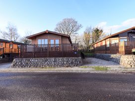 Log cabin with wooden deck and stone wall at Kingfisher Lodge