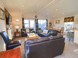 A living room with sofas and a dining area at Kingfisher Lodge