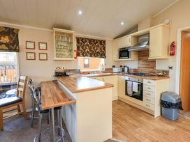 A kitchen with cabinets, a gas stove, and bar stools at Kingfisher Lodge 
