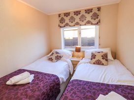 A bedroom with two beds and a lamp at Kingfisher Lodge 