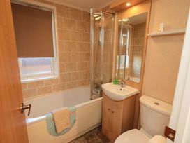 A bathroom with a bathtub, shower, sink and toilet at Kingfisher Lodge