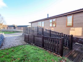 An outdoor area with a wooden lodge and railing at Kingfisher Lodge
