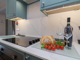 A kitchen with cooking stove, bread, tomatoes, and wine at Cheyne Cottage in Fylingthorpe
