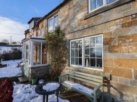 An exterior view of a house with a bench and windows at Cheyne Cottage in Fylingthorpe