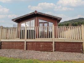 A wooden cabin with decking and railings at Monach 1