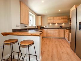 A kitchen with wooden cabinets and bar stools at 3 Rope Walk in St. Austell