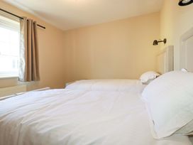 A bedroom with two beds and a window at 3 Rope Walk in St. Austell
