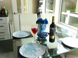 A dining table with plates, a glass of red drink, and a wine bottle at Seton Sands Caravan Park - Holiday Accommodation 13391, Cockenzie And Port Seton