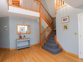 A hallway with a staircase and console table at Lady Of Lourdes in Whitchurch, Herefordshire
