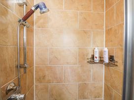 A shower with a metal shelf holding shampoo bottles at Lady Of Lourdes in Whitchurch, Herefordshire