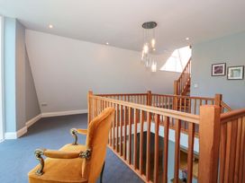 A hallway with a chair and staircase at Lady Of Lourdes in Whitchurch, Herefordshire