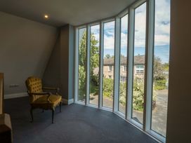 A sitting room with a chair and large windows at Lady Of Lourdes in Whitchurch, Herefordshire