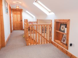 A hallway with a stair railing and pictures at Storey and Half House Annagry