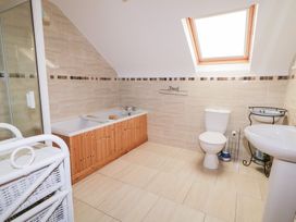 A bathroom with a bathtub, shower, toilet and sink at Storey and Half House in Annagry