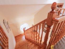 A staircase with a railing and decorative window at Storey and Half House in Annagry