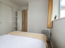 A bedroom with a bed, mirror, wardrobe, and shelf at Cove Retreat in Penzance