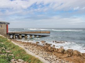 A pier extending into the water with rocks at Cove Retreat in Penzance