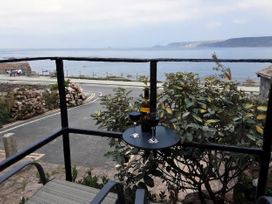 A balcony with wine glasses and a bottle overlooking the sea at Cove Retreat in Sennen Cove