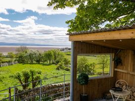 An outdoor area with a table and chair overlooking greenery at Little Hut in Grange-Over-Sands