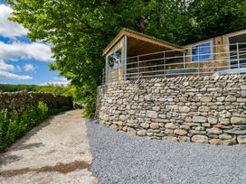 An outdoor view of a wooden structure and stone wall at Little Hut in Grange-Over-Sands