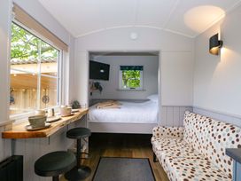 A living room with a table and chairs next to a bed at Little Hut in Grange-Over-Sands