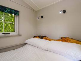 A bedroom with a bed and wood headboard at Little Hut in Grange-Over-Sands