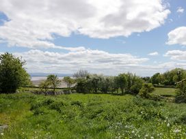 A view of trees and grass with a distant water body at Little Hut in Grange-Over-Sands