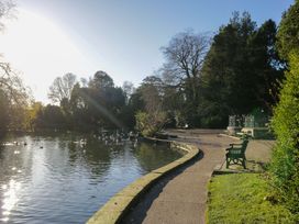 A pond with a pathway and bench beside it at Little Hut in Grange-Over-Sands