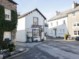A corner building with a sign for CARTMEL and a telephone booth at Little Hut in Grange-Over-Sands