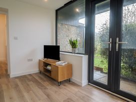 A living room with a television and sliding doors at Little Poppes Lawn in Holditch near Hawkchurch