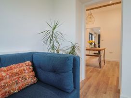 A living room with a couch and a view to a kitchen table with flowers at Little Poppes Lawn in Holditch near Hawkchurch